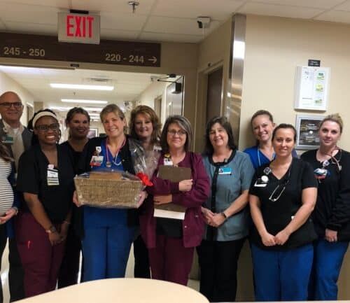 Healthcare team gathered in hospital hallway celebrating employee of the month with gift basket