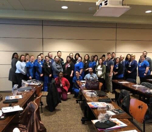 Large group of new Kettering Health employees posing together in conference room