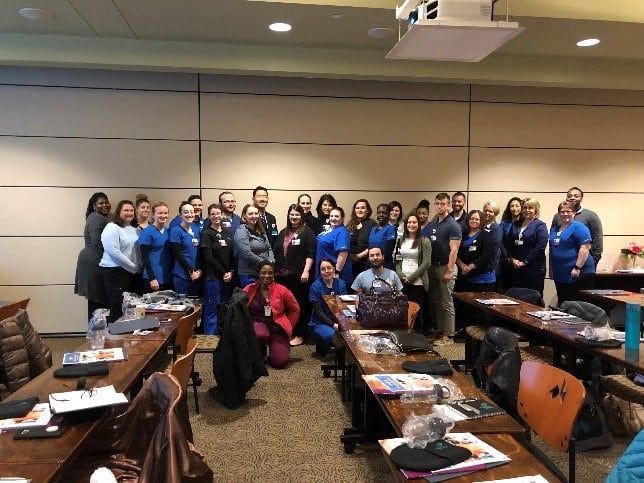 Large group of new Kettering Health employees posing together in conference room