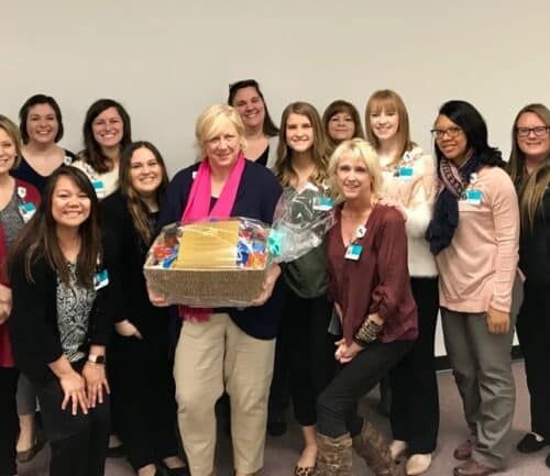 Healthcare team celebrating with gift basket presentation to colleague in office setting