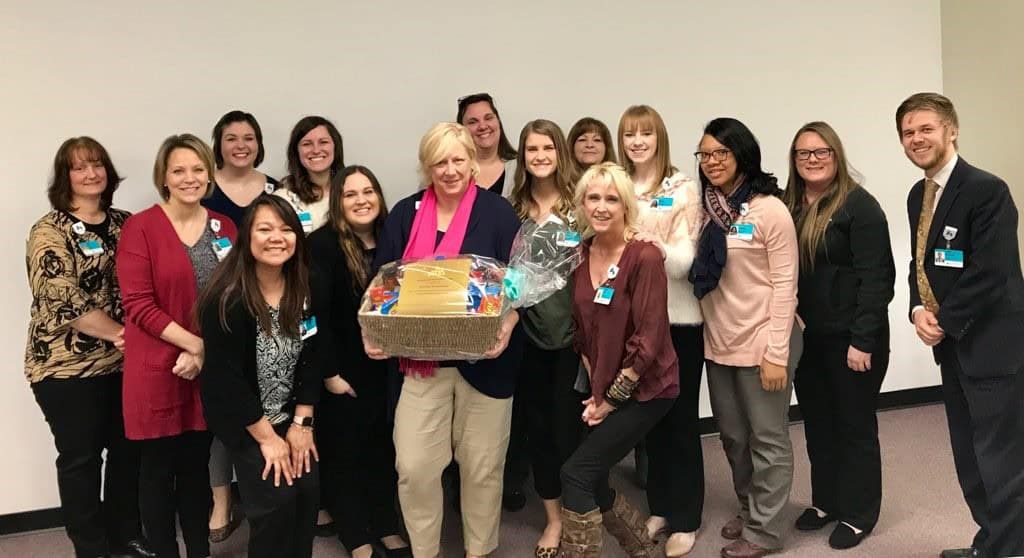 Healthcare team celebrating with gift basket presentation to colleague in office setting