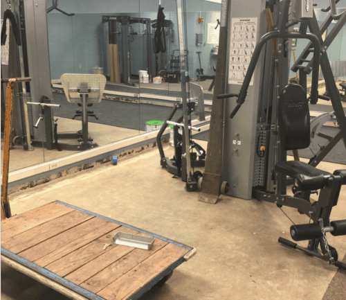 Modern fitness room with weight machines, mirrors, and wooden platform at Kettering Health.