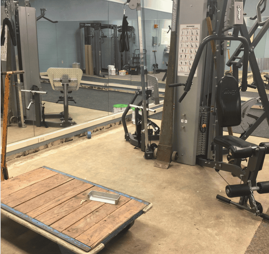 Modern fitness room with weight machines, mirrors, and wooden platform at Kettering Health.