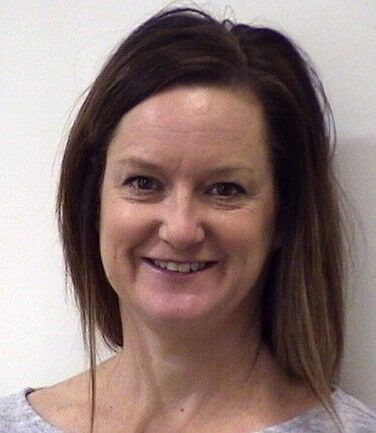 Professional headshot of smiling healthcare provider with brown hair against white background