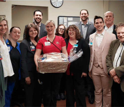 Healthcare team celebrating employee recognition with gift basket in hospital setting
