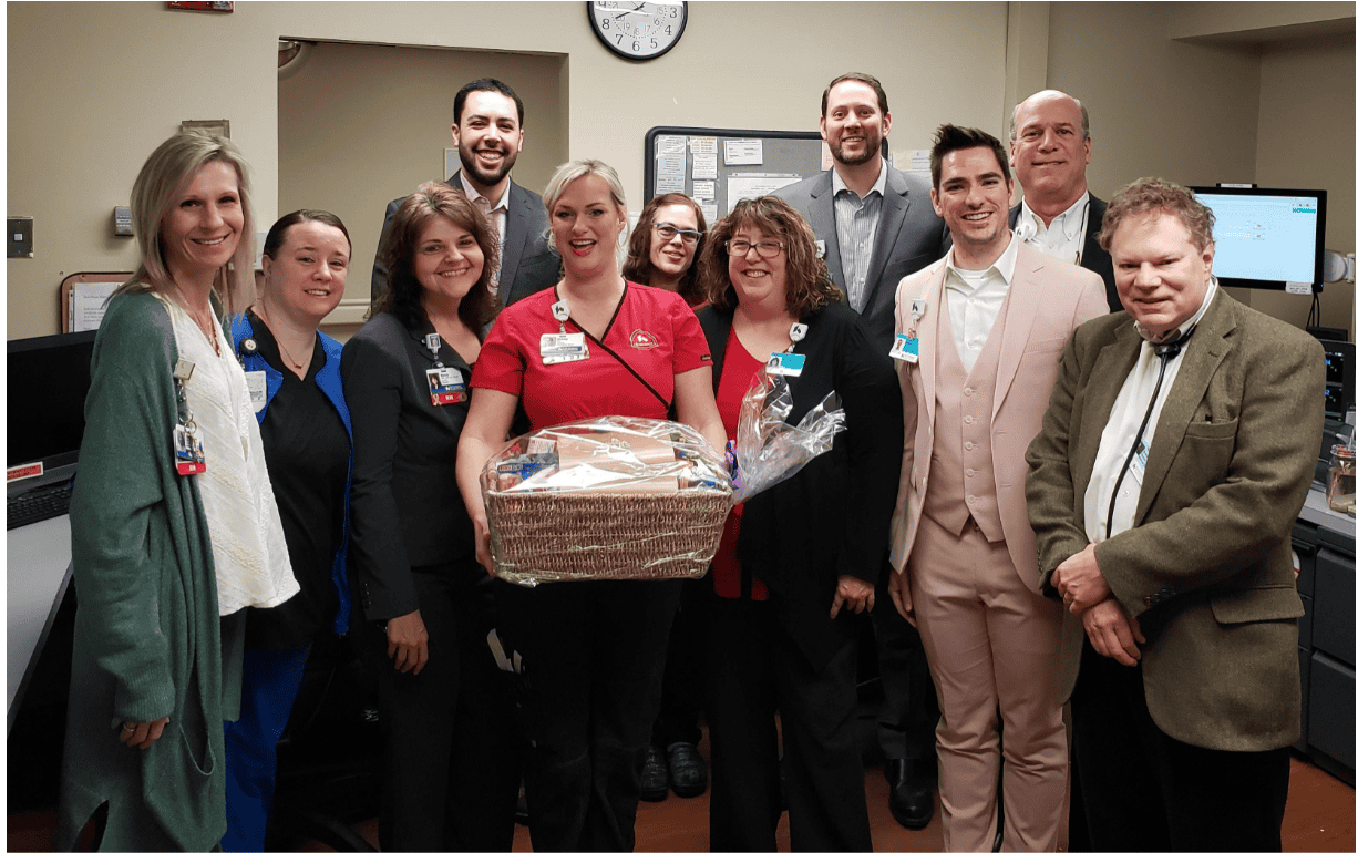 Healthcare team celebrating employee recognition with gift basket in hospital setting