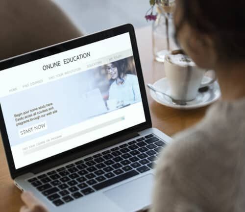 Student browsing online education website on laptop with coffee cup nearby