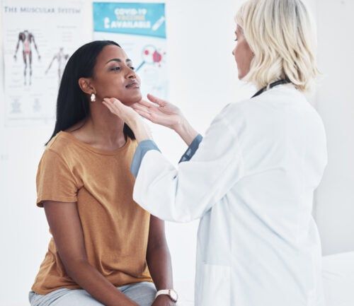 Doctor examining patient's throat and neck during medical consultation