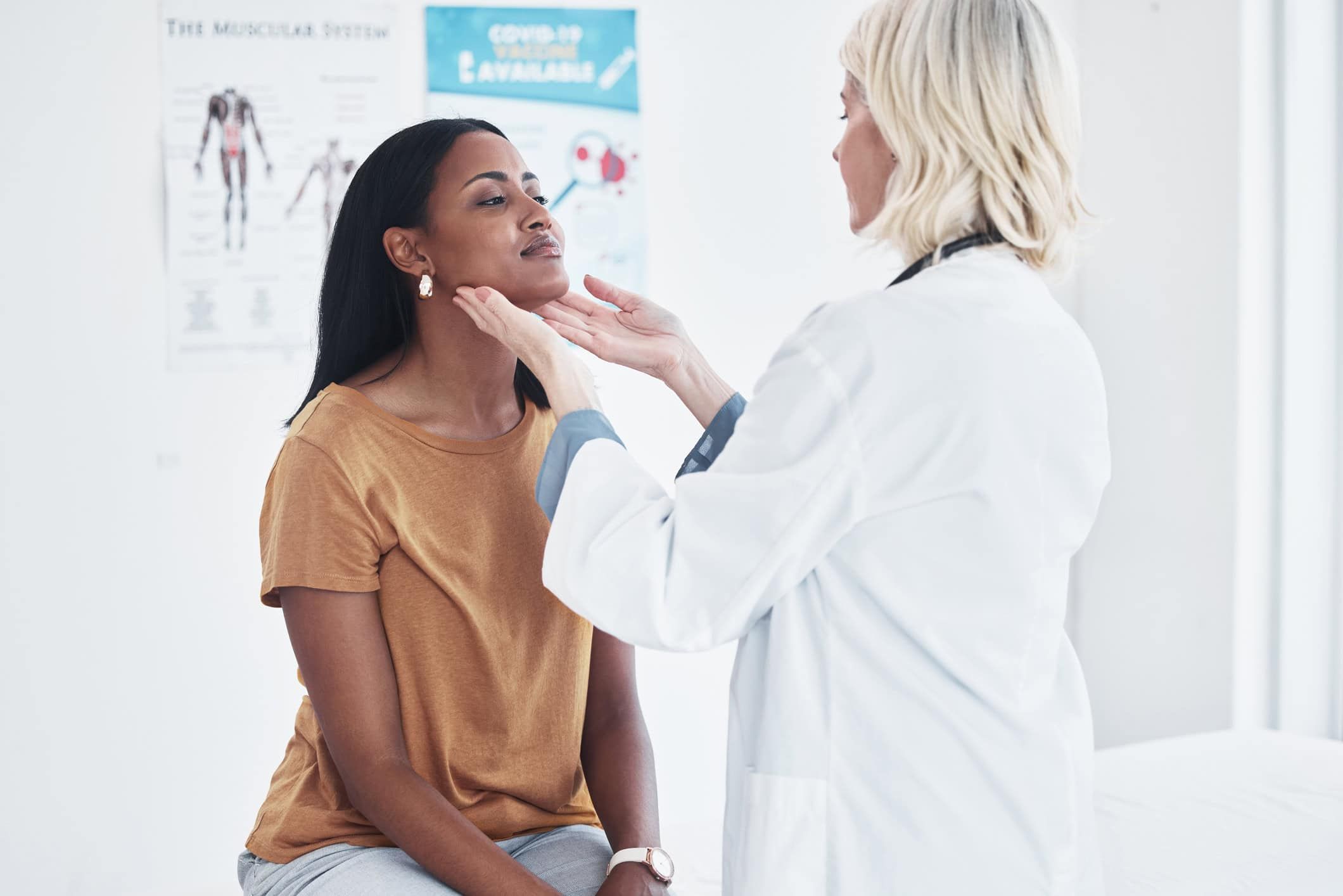Doctor examining patient's throat and neck during medical consultation