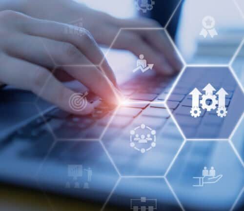 Hands typing on laptop with hexagonal digital icons representing healthcare operational processes