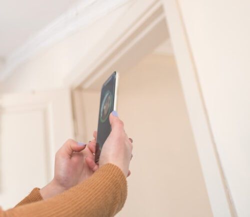 Woman holding smartphone up for facial recognition or selfie in bright interior