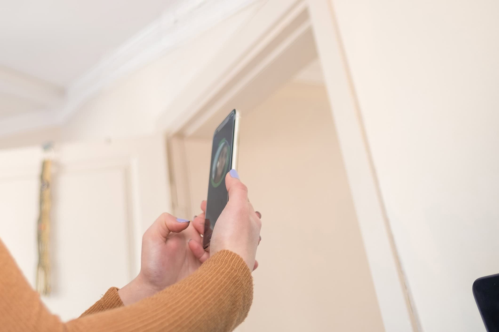 Woman holding smartphone up for facial recognition or selfie in bright interior