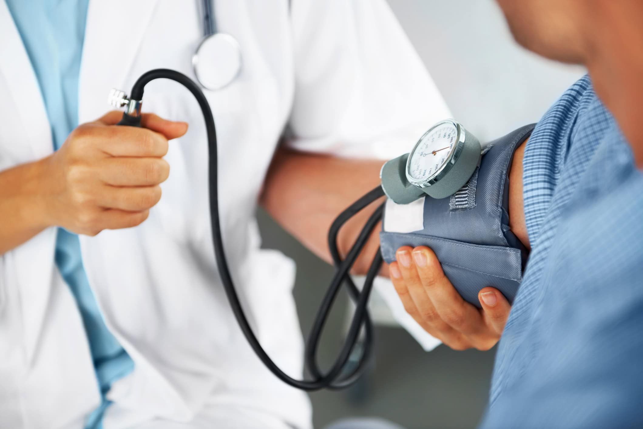Healthcare provider taking patient's blood pressure with sphygmomanometer during medical examination