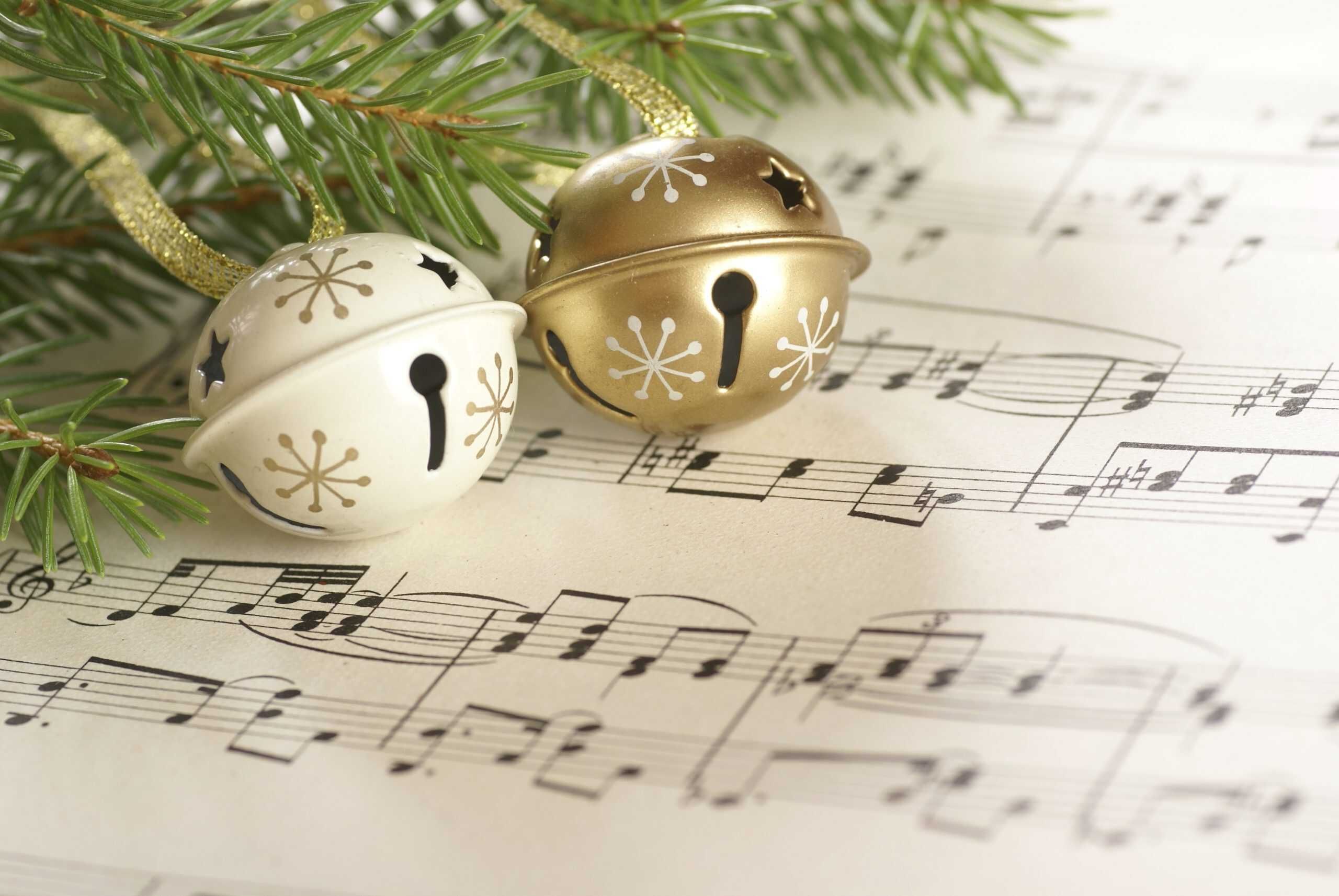 Christmas jingle bells and evergreen branches resting on sheet music