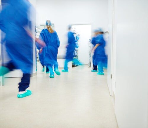 Medical team in blue scrubs rushing through hospital hallway during emergency