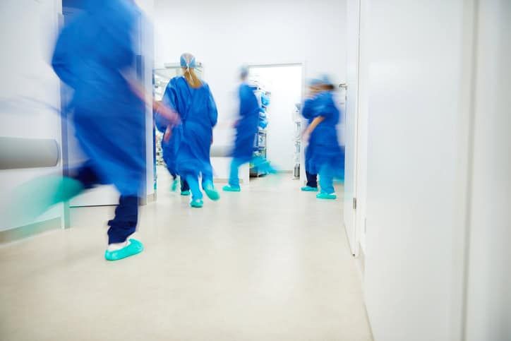 Medical team in blue scrubs rushing through hospital hallway during emergency
