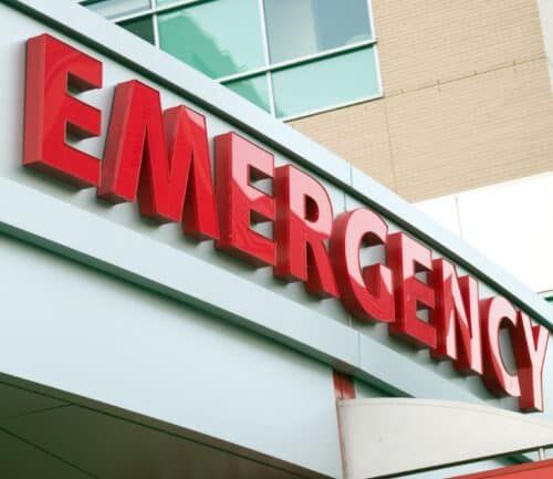 Red "EMERGENCY" sign on exterior of modern hospital building