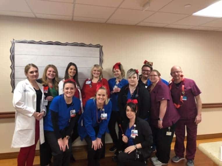 Healthcare team wearing red and blue scrubs posing together for Go Red for Women event