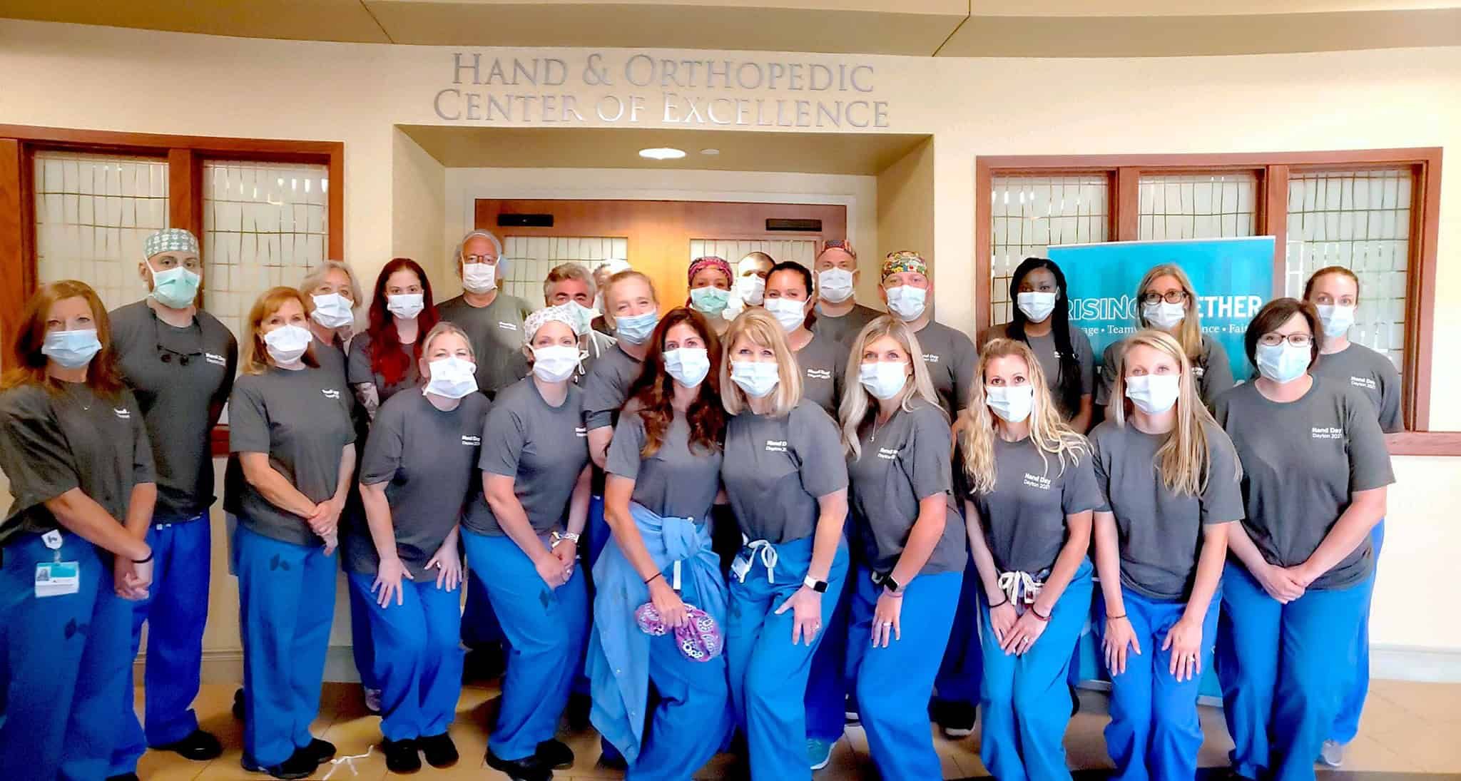 Medical staff in scrubs and masks posing together at Hand & Orthopedic Center of Excellence