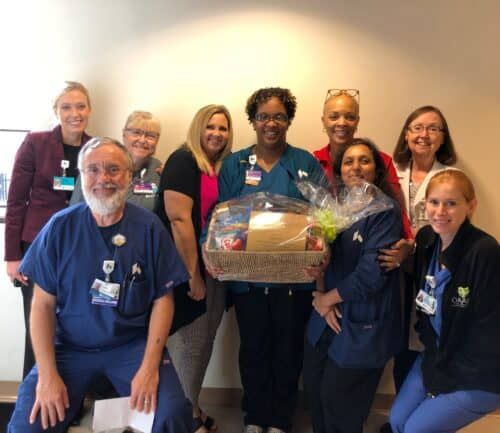 Healthcare team members celebrating with gift basket presentation in hospital setting