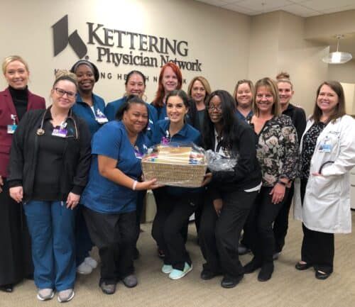 Healthcare staff members posing together with gift basket at Kettering Physician Network office