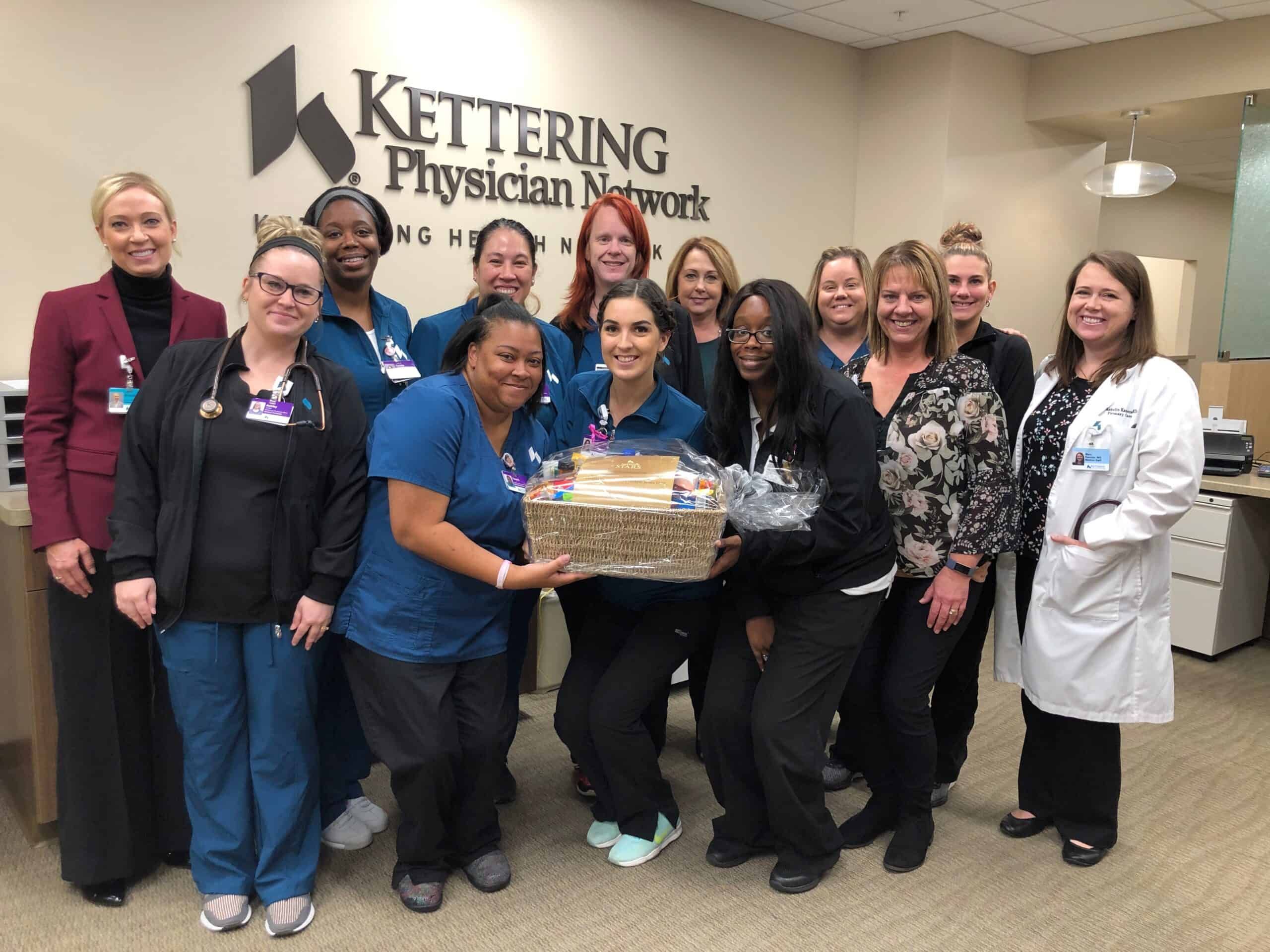 Healthcare staff members posing together with gift basket at Kettering Physician Network office