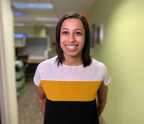 Smiling woman in colorblock shirt standing in bright hospital hallway