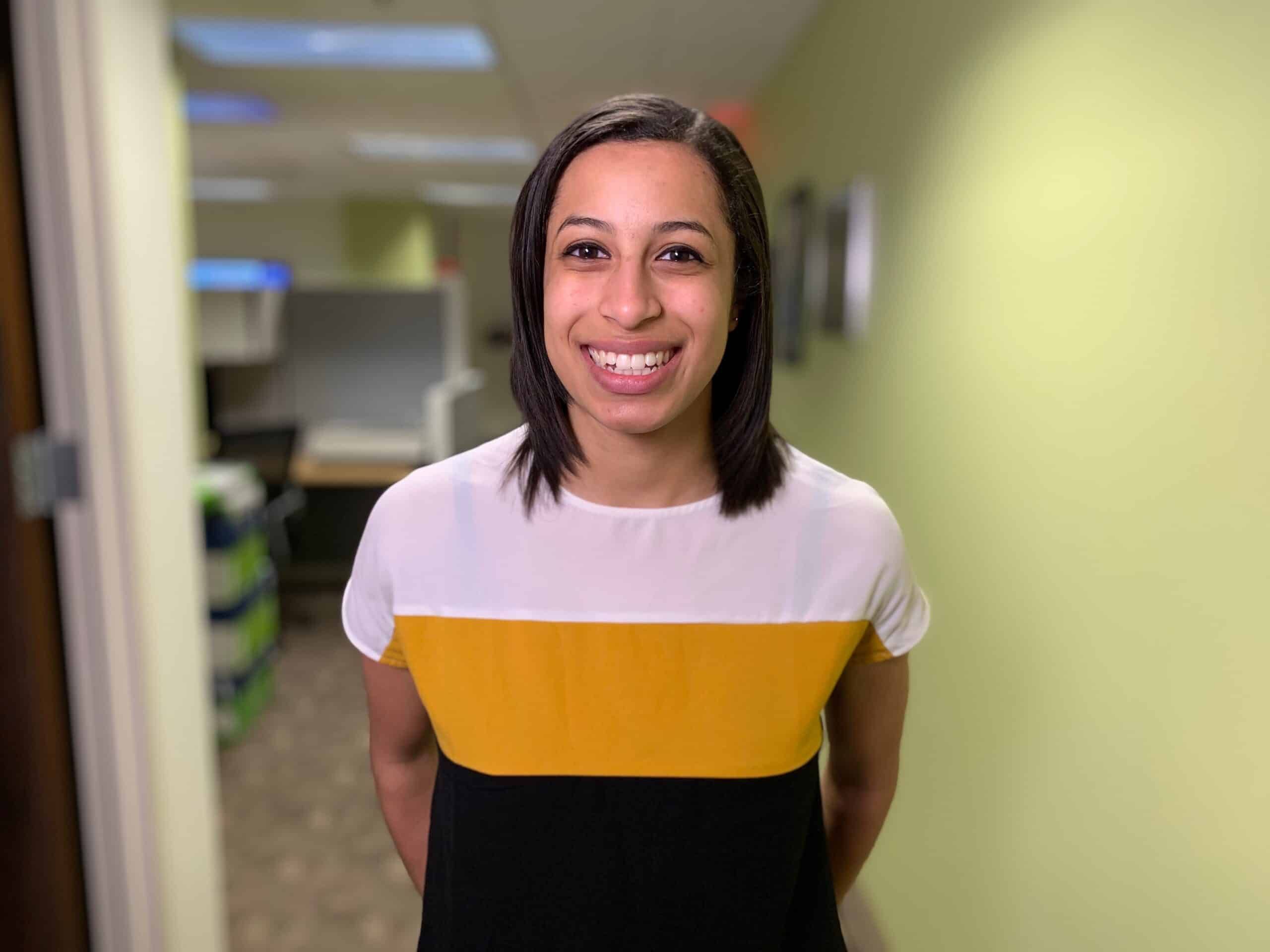 Smiling woman in colorblock shirt standing in bright hospital hallway