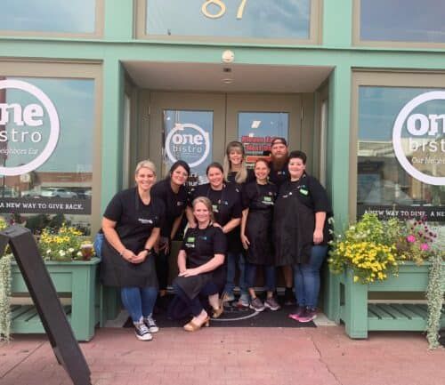 Group of restaurant staff members posing together outside One Bistro entrance