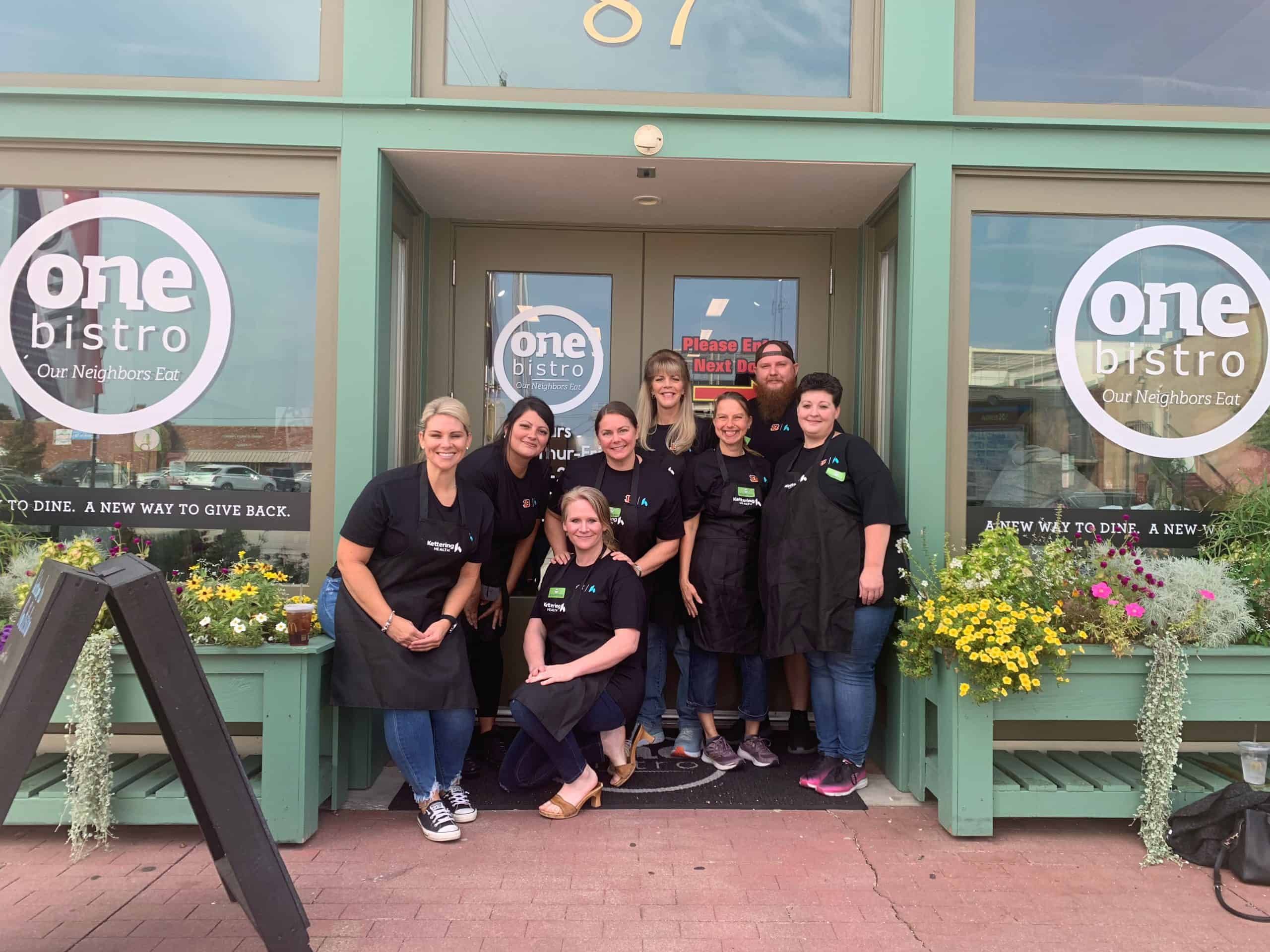 Group of restaurant staff members posing together outside One Bistro entrance