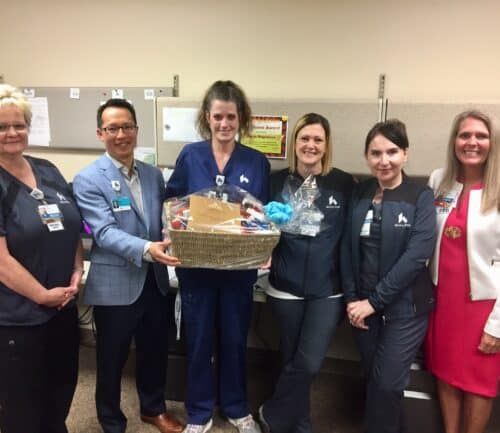 Healthcare staff presenting gift basket to colleagues in medical office setting