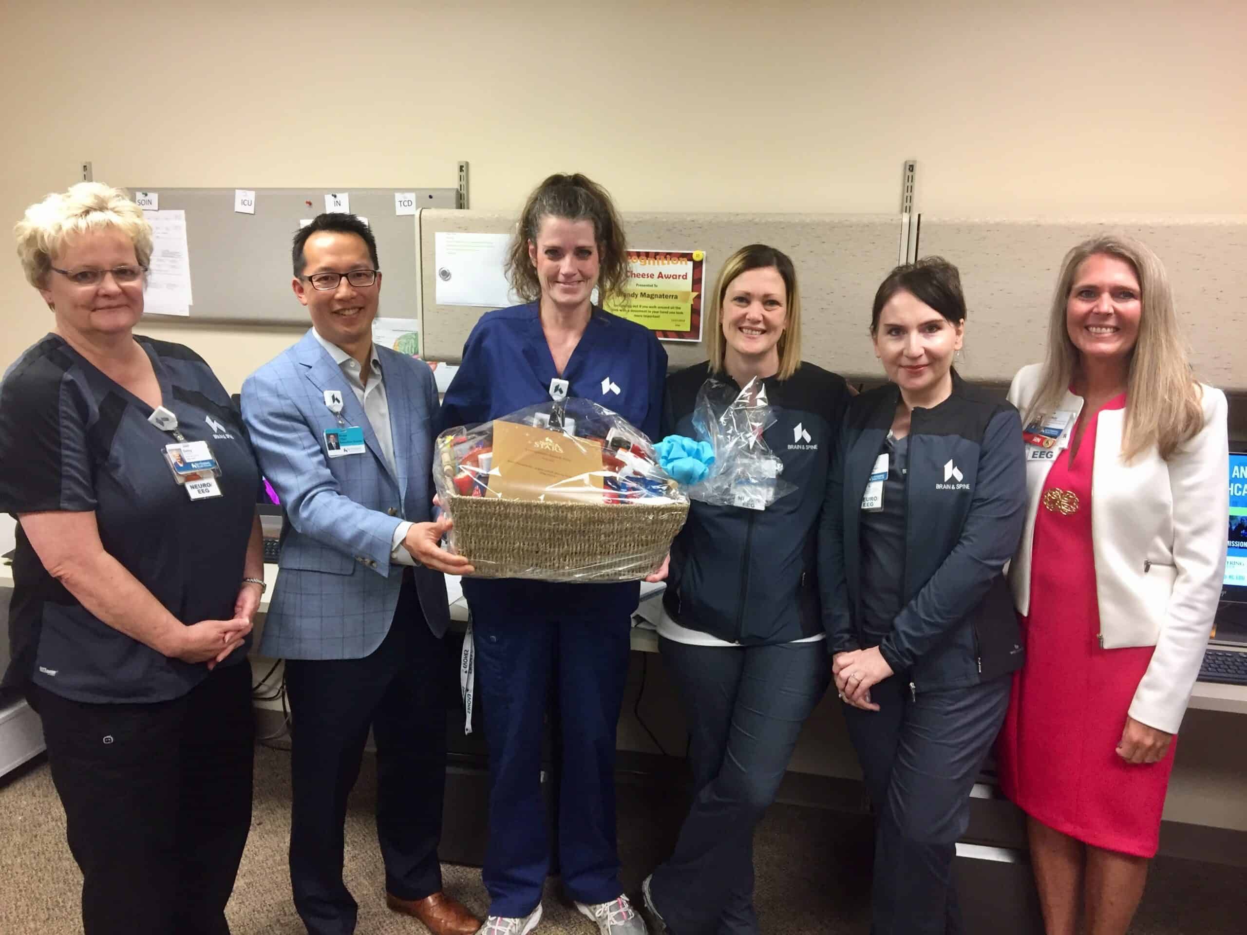 Healthcare staff presenting gift basket to colleagues in medical office setting