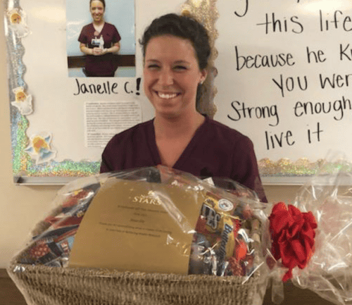 Healthcare worker Janelle holds gift basket with inspirational wall message behind her