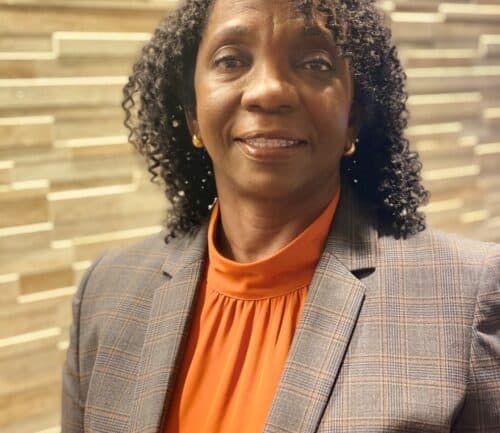 Professional headshot of Jannet Ward wearing gray blazer and orange blouse