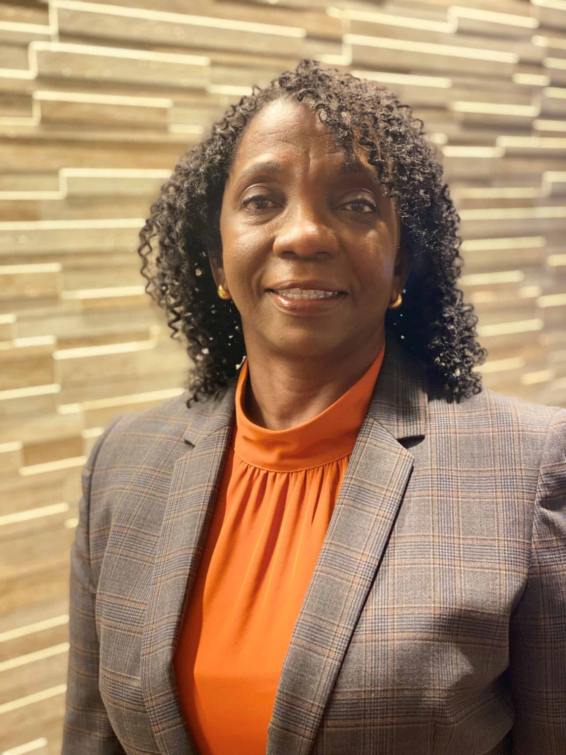 Professional headshot of Jannet Ward wearing gray blazer and orange blouse