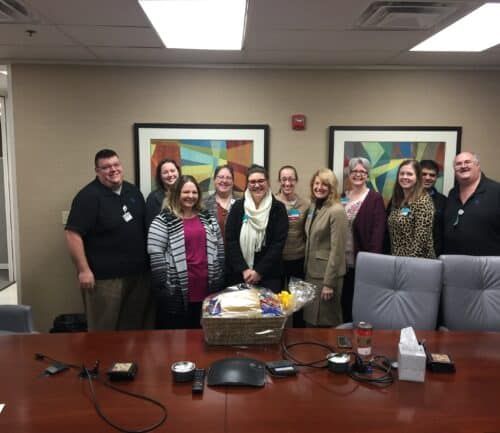 Group of healthcare employees celebrating with gift basket in conference room