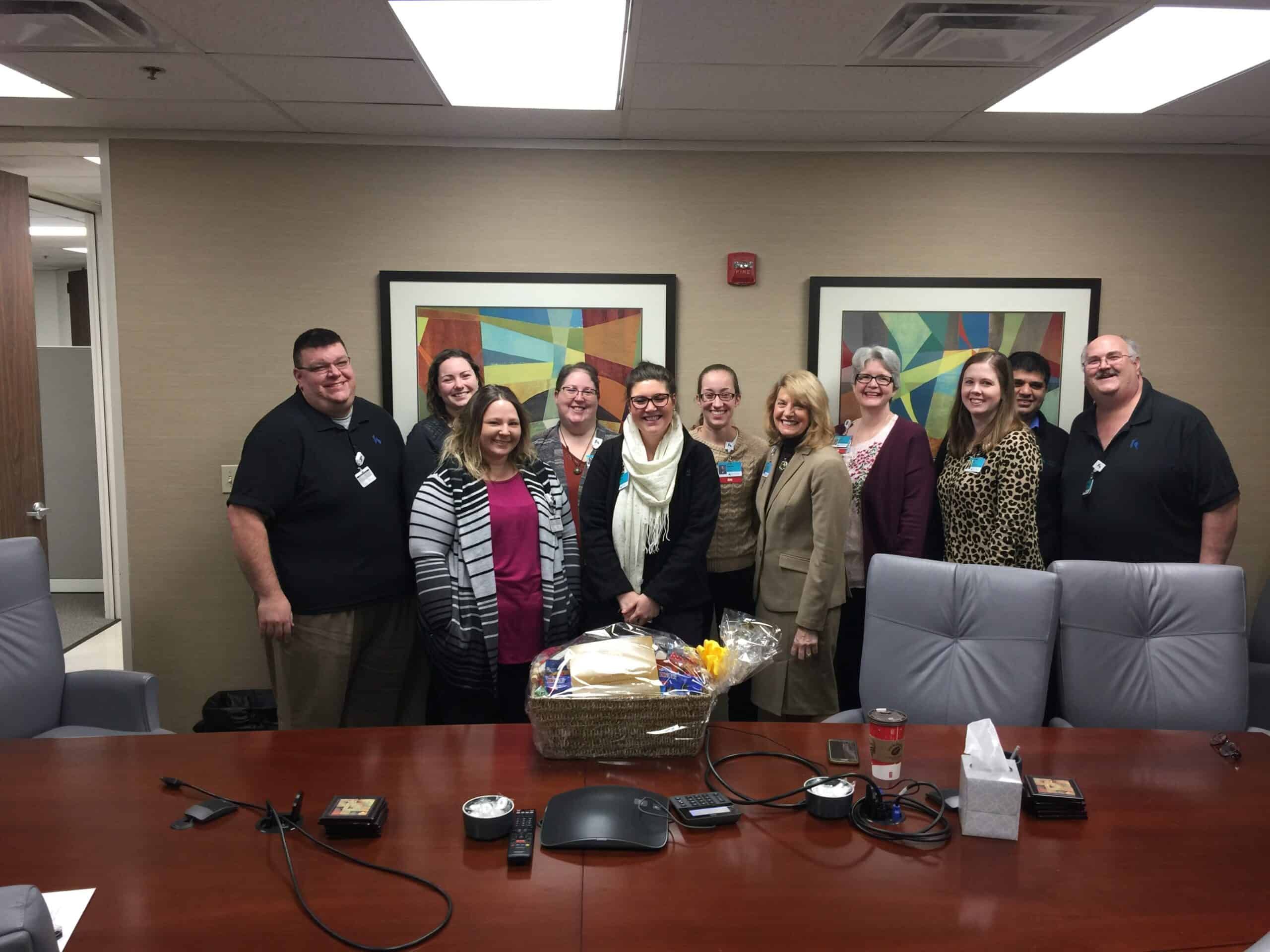 Group of healthcare employees celebrating with gift basket in conference room