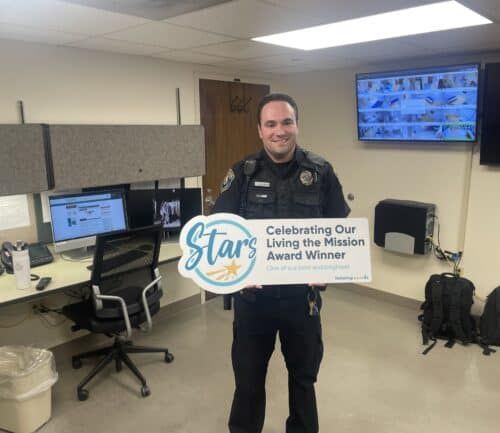 Security officer Nathan Foster holding Stars Living the Mission Award in office workspace