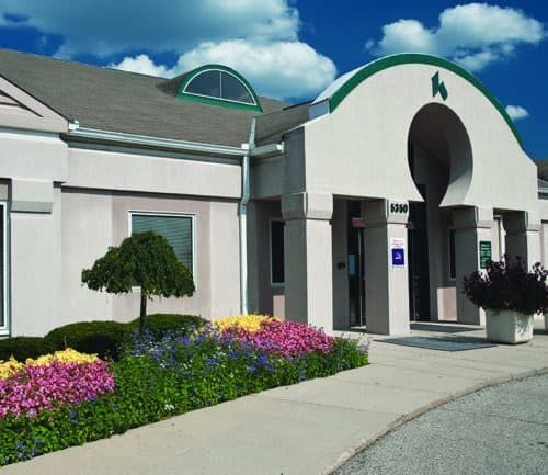 Modern Kettering Health medical building exterior with colorful flower gardens and green architectural accents.