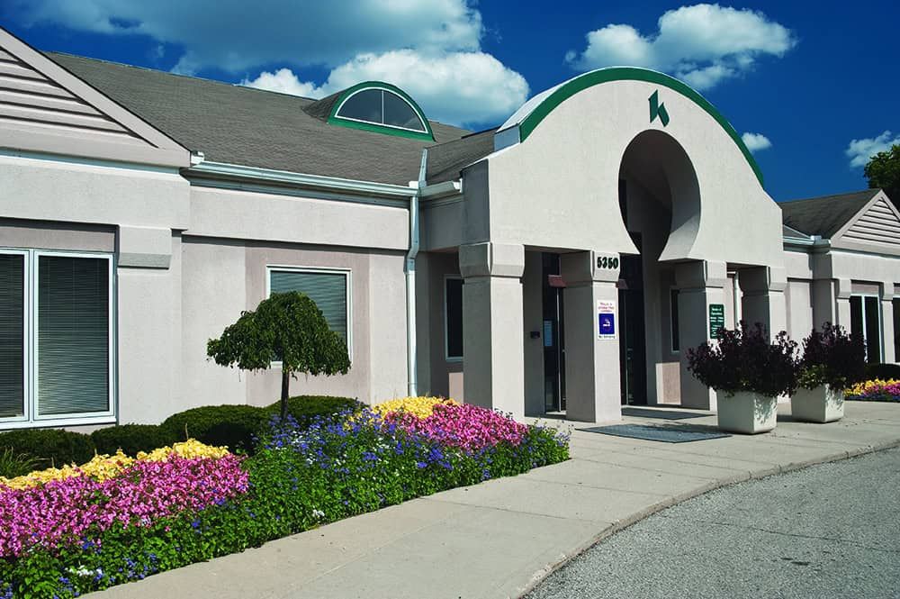 Modern Kettering Health medical building exterior with colorful flower gardens and green architectural accents.