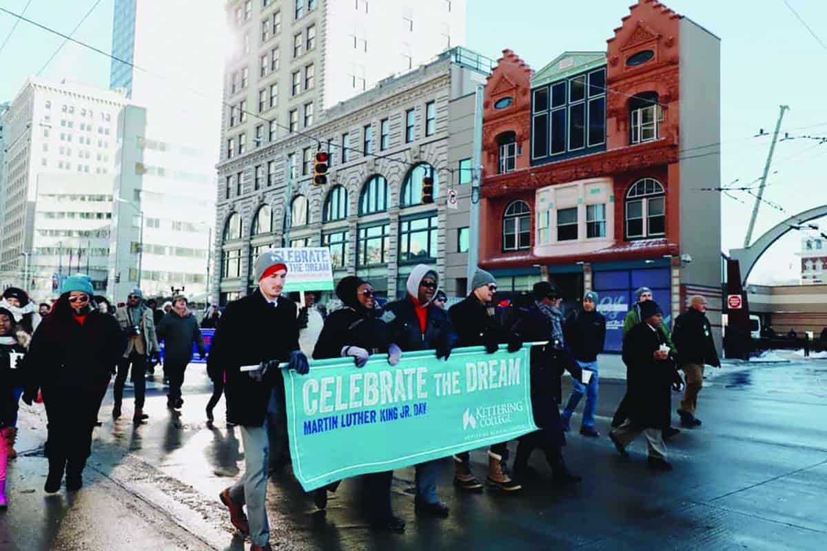 Group marching with "Celebrate the Dream Martin Luther King Jr. Day" banner on snowy street