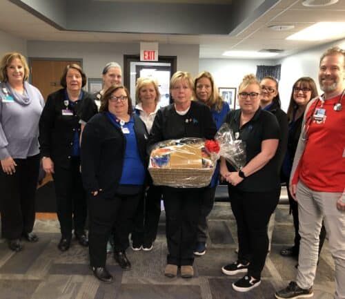 Healthcare team celebrating employee recognition with gift basket presentation in hospital setting