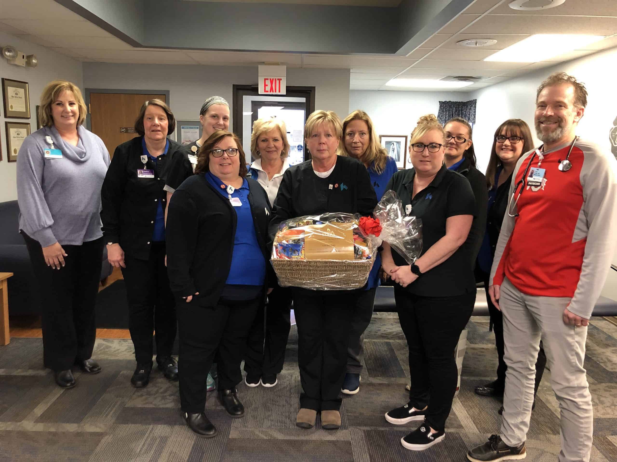 Healthcare team celebrating employee recognition with gift basket presentation in hospital setting