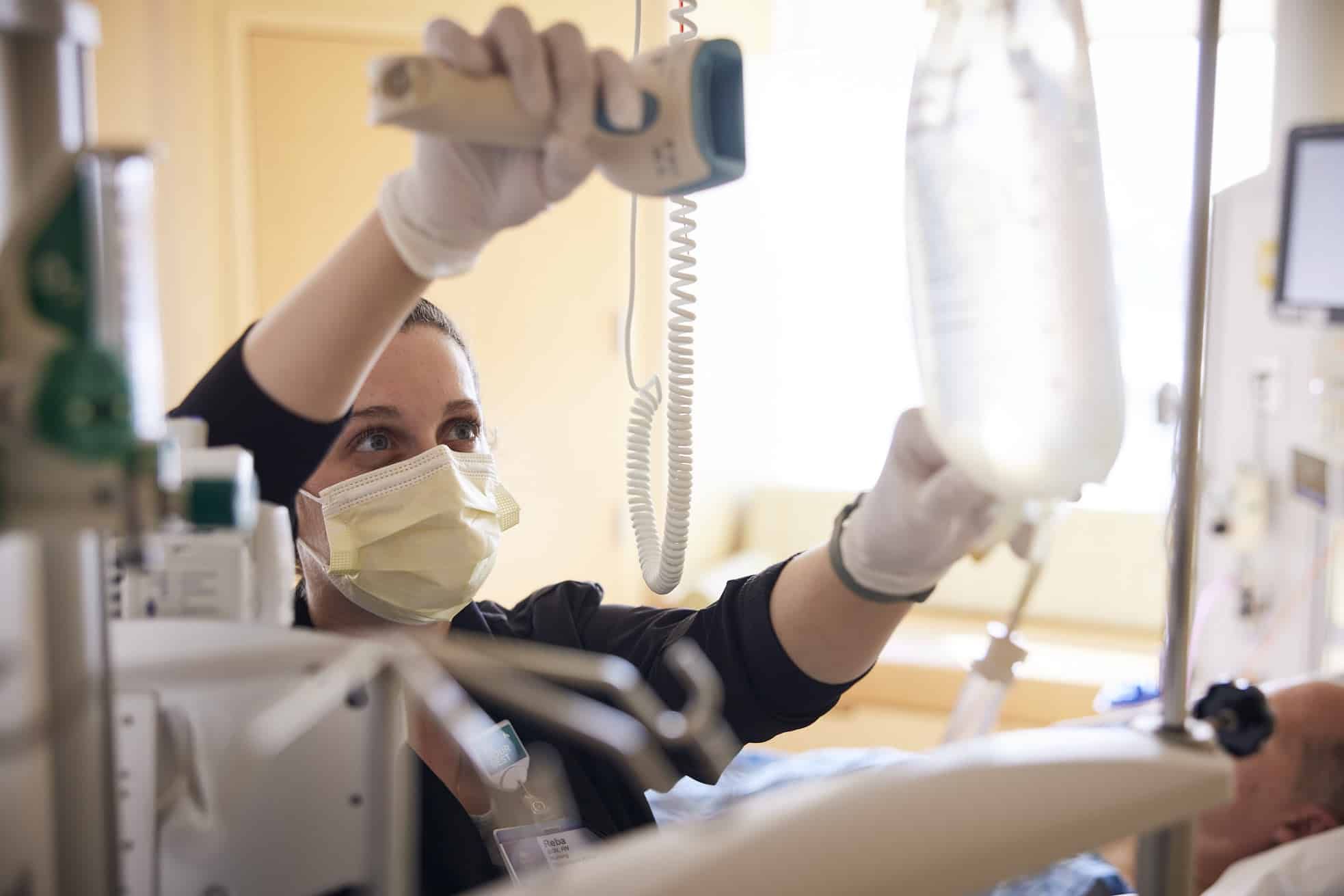 Healthcare worker in mask and gloves operating medical imaging equipment in hospital room