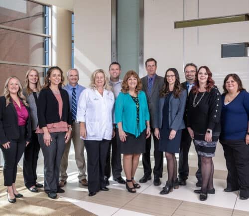 Group of Kettering Health pharmacy team members posing together in modern hospital lobby
