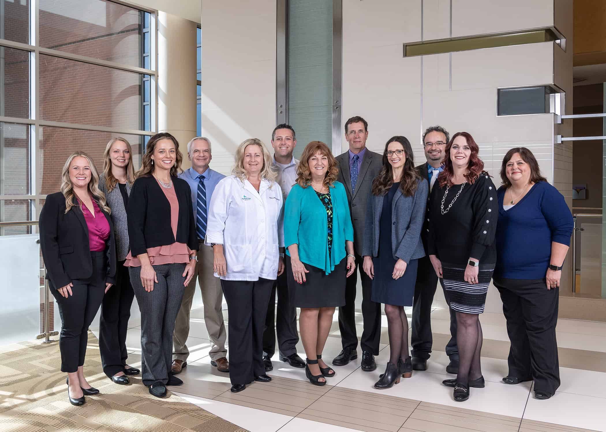 Group of Kettering Health pharmacy team members posing together in modern hospital lobby