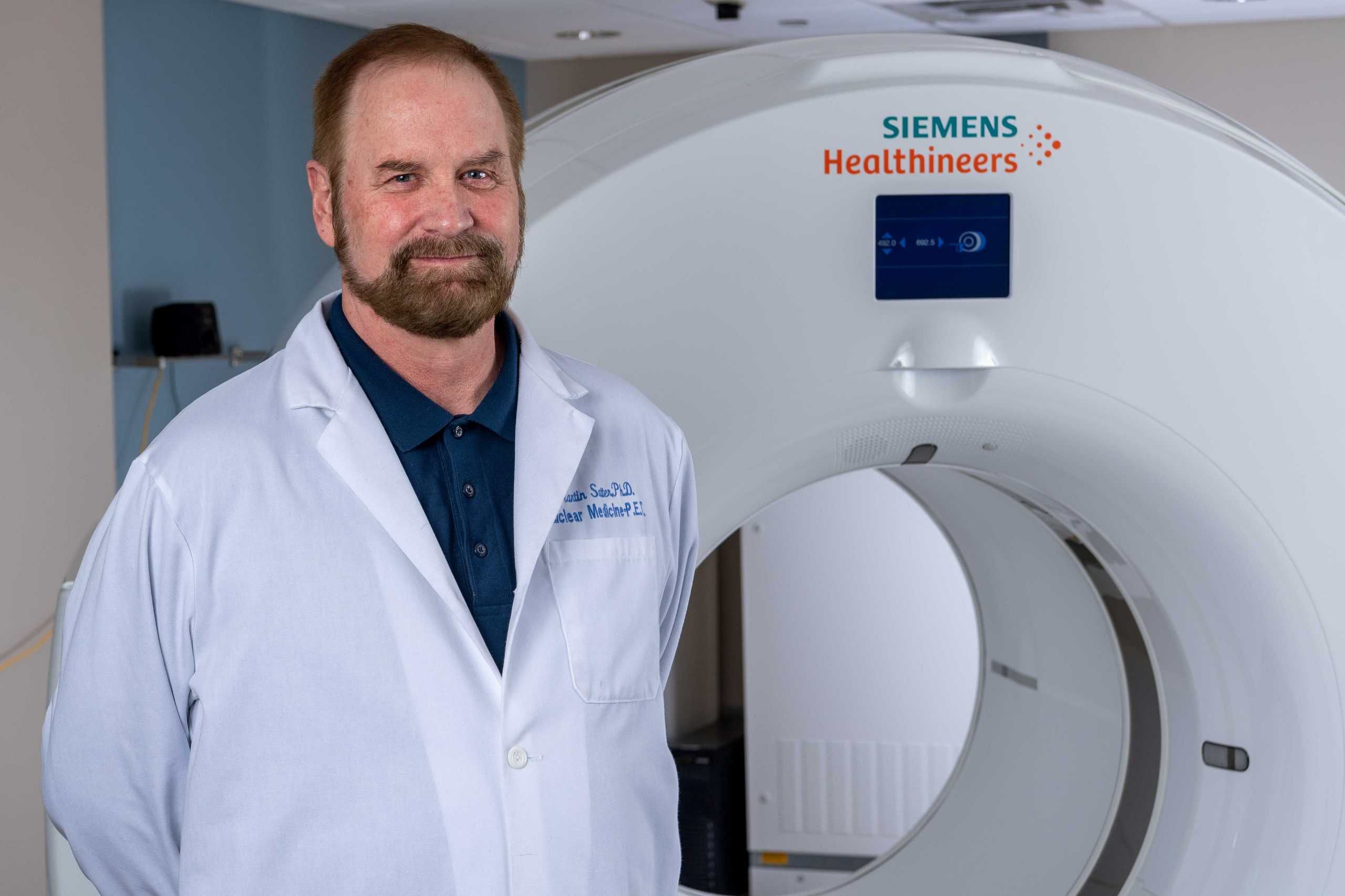 Doctor in white coat standing beside Siemens Healthineers MRI machine