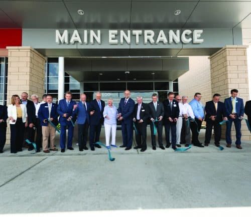 Group of people participating in ribbon cutting ceremony at hospital main entrance