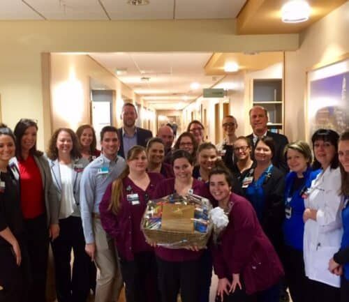 Healthcare staff celebrating with gift basket in hospital hallway