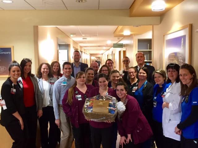Healthcare staff celebrating with gift basket in hospital hallway